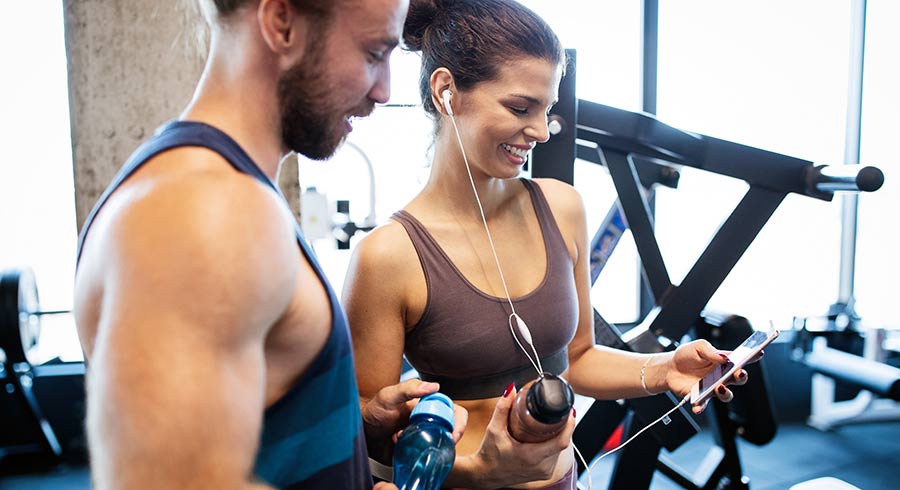 שני מאמני כושר בחדר כושר מביטים על הסלולרי שבו כרטיס ביקור דיגיטלי